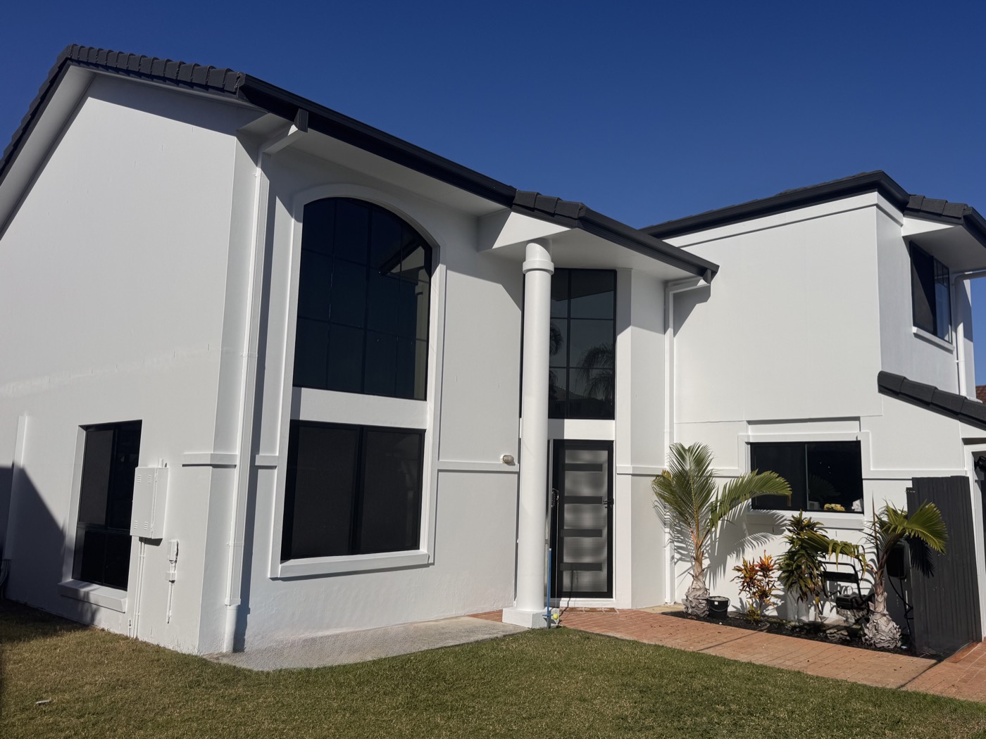 House front after full exterior repaint — crisp white with charcoal accents